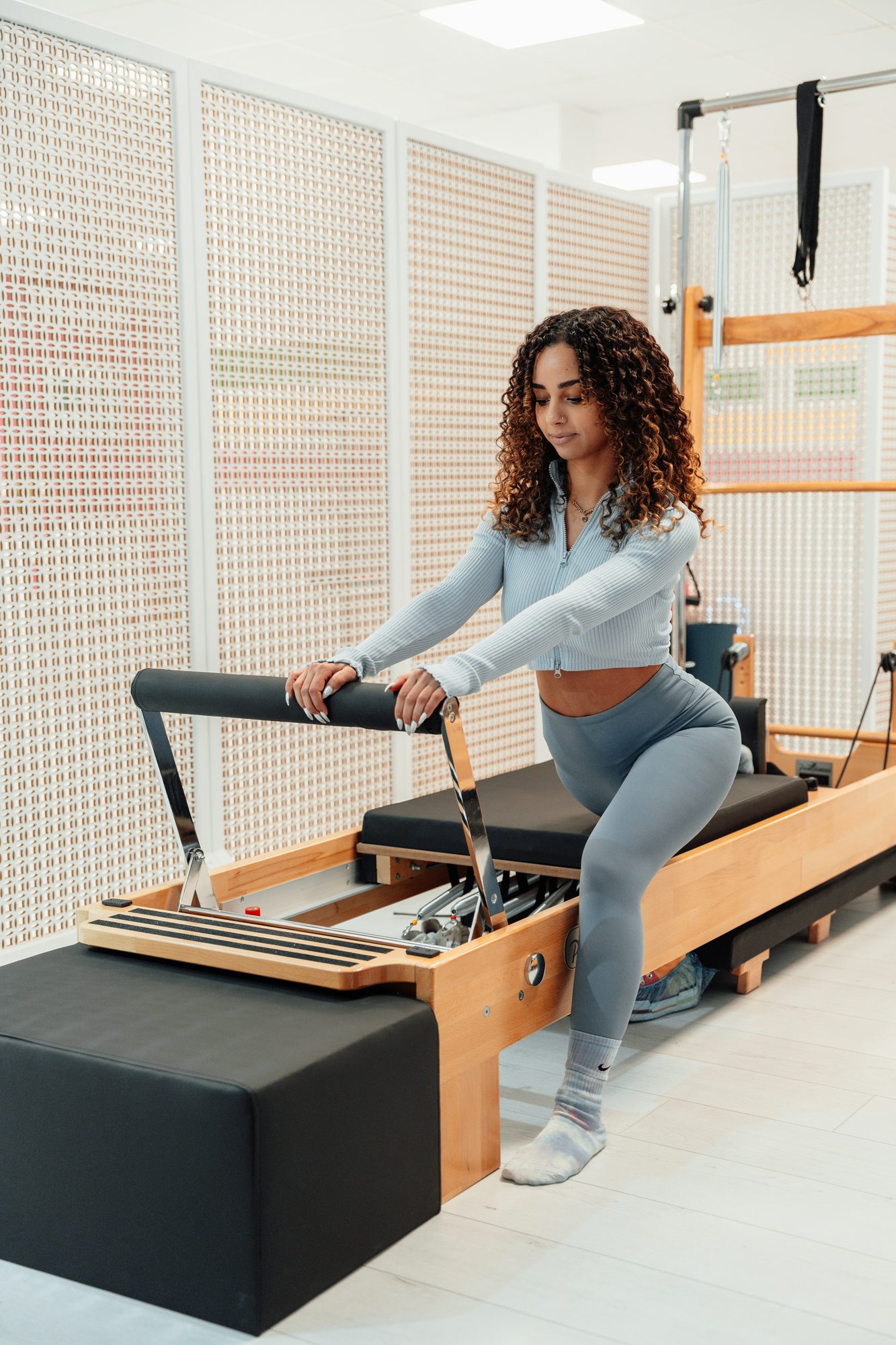 A woman setting up at the footbar of a wooden reformer